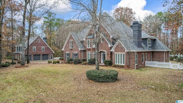 view of front of property with a garage, brick siding, fence, a front lawn, and a chimney