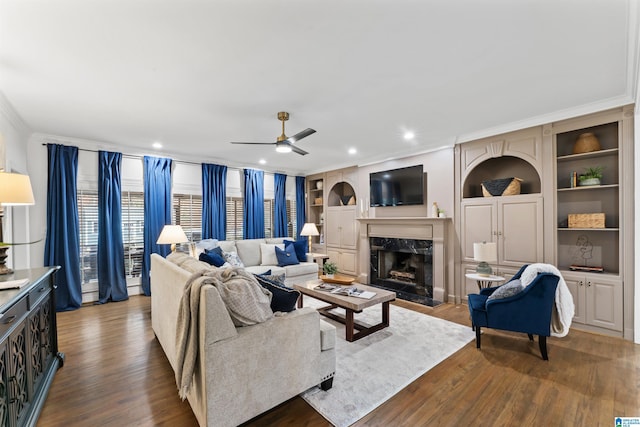 living room featuring a fireplace, wood-type flooring, built in features, and crown molding