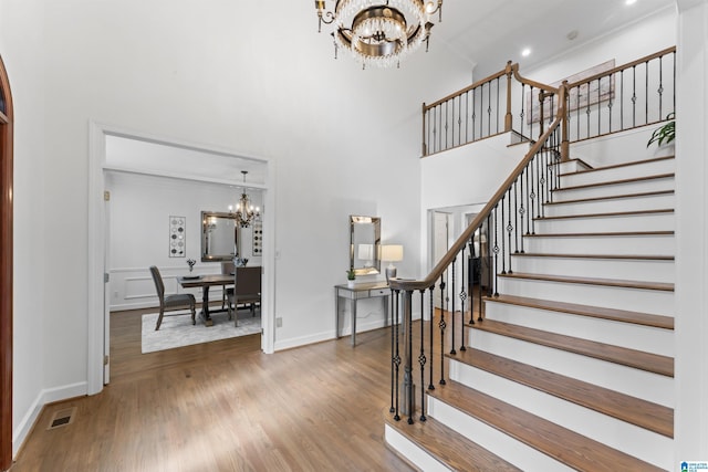 stairs with hardwood / wood-style floors, a notable chandelier, and a high ceiling