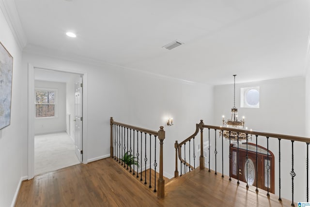 hallway featuring ornamental molding, wood-type flooring, and a notable chandelier