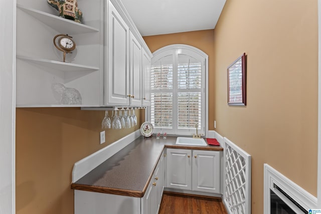 kitchen with dark hardwood / wood-style flooring, white cabinets, and sink