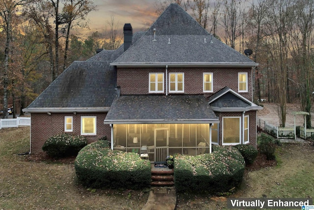 back house at dusk featuring a sunroom