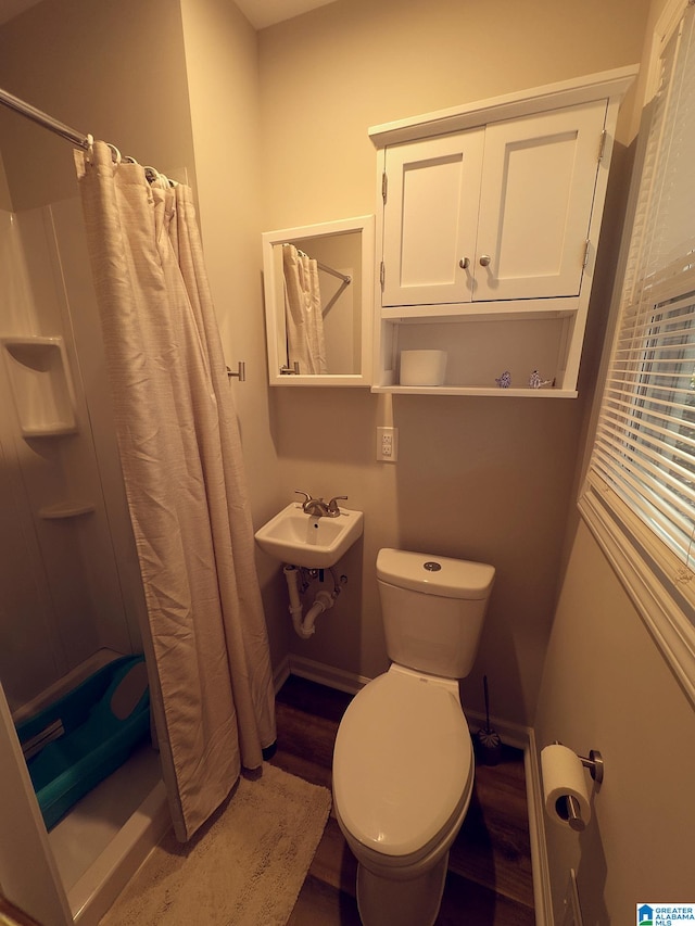 bathroom featuring curtained shower, toilet, wood-type flooring, and sink