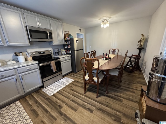 kitchen featuring light stone countertops, appliances with stainless steel finishes, dark hardwood / wood-style flooring, and gray cabinetry