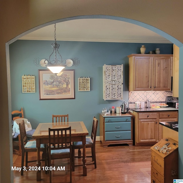 dining room featuring arched walkways, crown molding, and wood finished floors