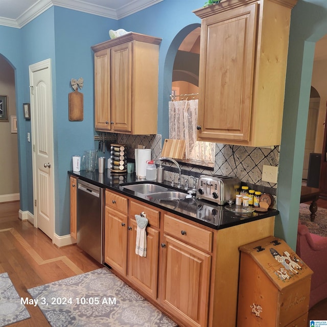 kitchen featuring arched walkways, light wood-style flooring, ornamental molding, a sink, and dishwasher