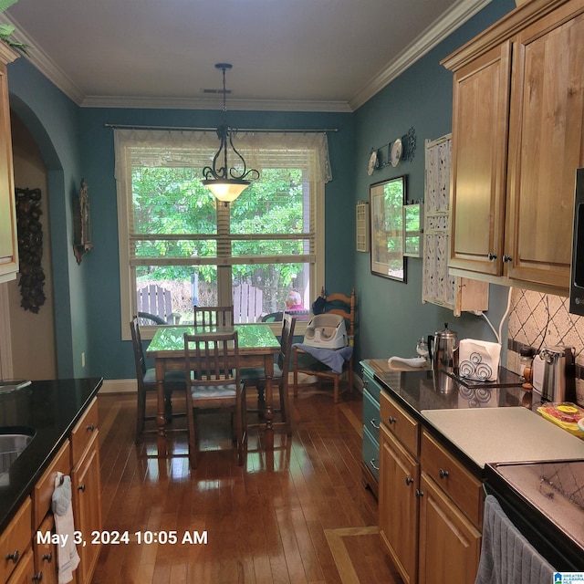 kitchen featuring brown cabinetry, arched walkways, dark wood-style flooring, and crown molding