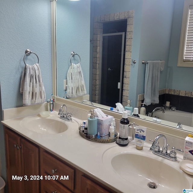 bathroom with a stall shower, a sink, and double vanity