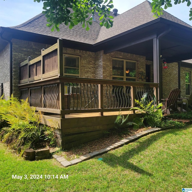 back of house featuring a balcony, a yard, a shingled roof, and brick siding