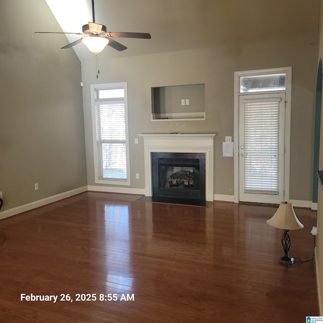 unfurnished living room featuring ceiling fan, wood finished floors, a fireplace with flush hearth, and baseboards