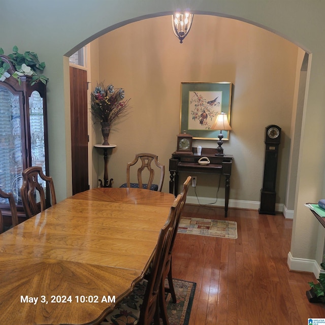 dining room featuring arched walkways, wood-type flooring, and baseboards