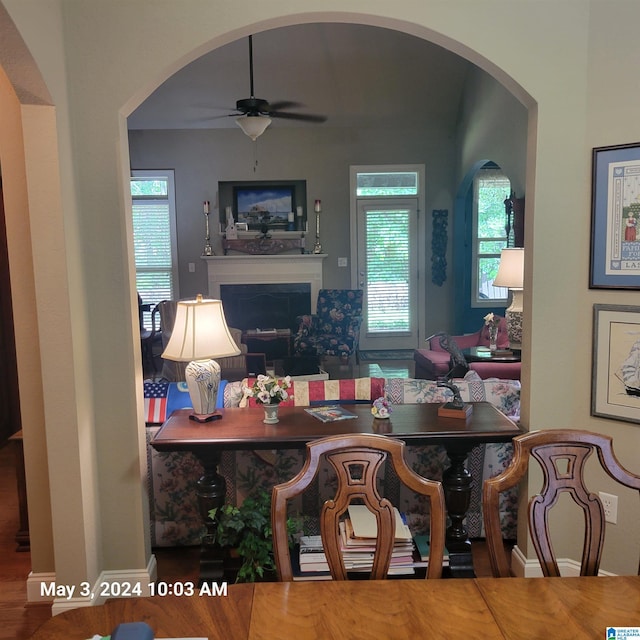 dining space with a fireplace, a ceiling fan, and wood finished floors