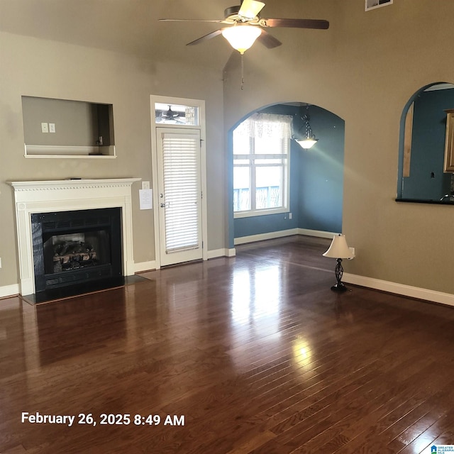 unfurnished living room with a fireplace with flush hearth, a ceiling fan, wood finished floors, visible vents, and baseboards