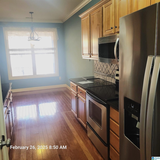 kitchen with stainless steel appliances, dark countertops, dark wood finished floors, and crown molding