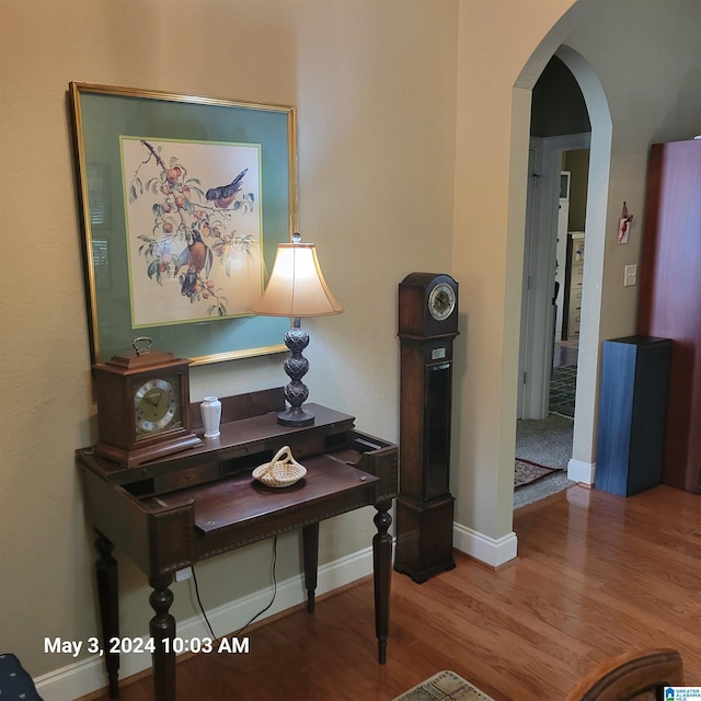 hall with arched walkways, wood finished floors, and baseboards