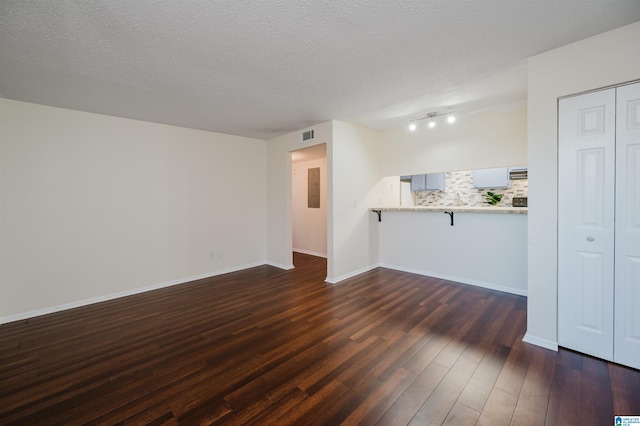 unfurnished living room featuring a textured ceiling and dark hardwood / wood-style floors