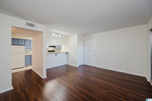 unfurnished living room with a textured ceiling and dark hardwood / wood-style floors