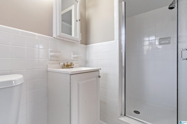 bathroom with vanity, a shower with shower door, tile walls, and toilet