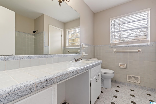 bathroom featuring vanity, toilet, a shower, and tile walls