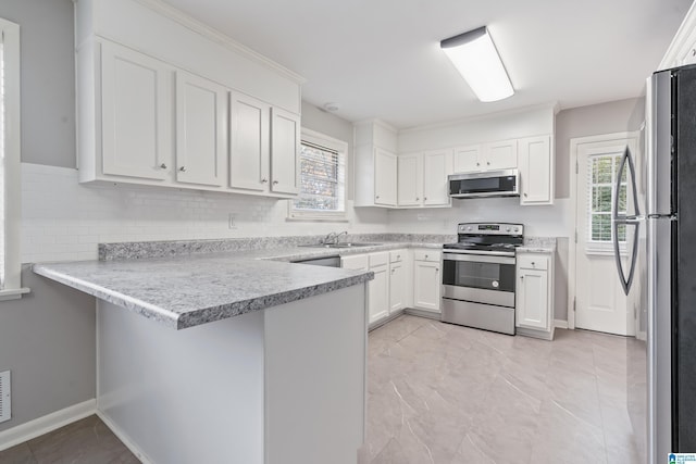 kitchen with white cabinetry, sink, kitchen peninsula, a breakfast bar area, and appliances with stainless steel finishes