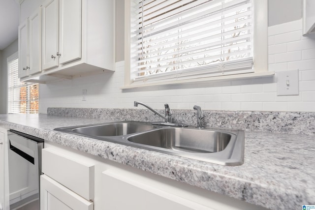 kitchen featuring backsplash, sink, white cabinets, and stainless steel dishwasher