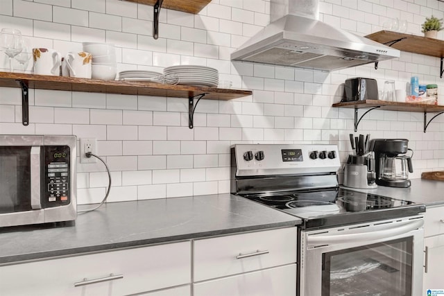 kitchen with white cabinets, appliances with stainless steel finishes, tasteful backsplash, and wall chimney exhaust hood