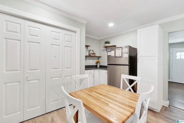 dining area with light hardwood / wood-style flooring and ornamental molding