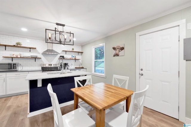 dining space featuring sink, light hardwood / wood-style floors, crown molding, and a notable chandelier