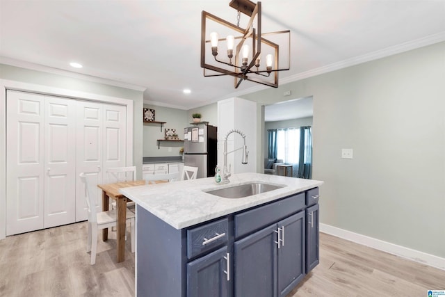 kitchen with stainless steel fridge, light wood-type flooring, a center island with sink, and sink