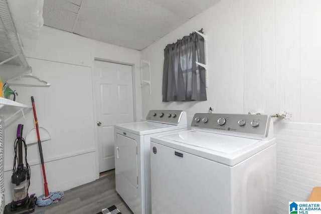 laundry area featuring hardwood / wood-style floors, separate washer and dryer, and wooden walls