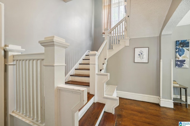 staircase featuring a textured ceiling and hardwood / wood-style flooring