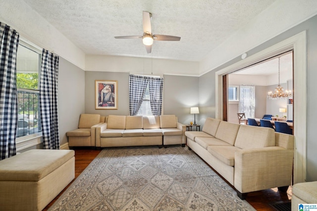 living room featuring a textured ceiling, ceiling fan with notable chandelier, and hardwood / wood-style flooring