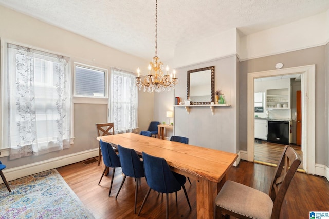 dining space featuring wood-type flooring, a textured ceiling, and an inviting chandelier