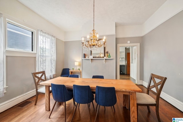 dining room with hardwood / wood-style floors, a textured ceiling, and a notable chandelier