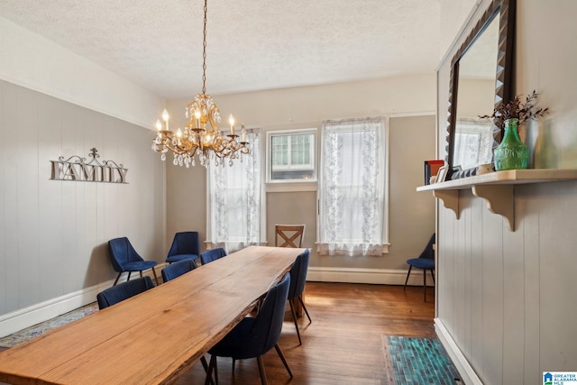 dining room featuring hardwood / wood-style flooring, a notable chandelier, a textured ceiling, and a baseboard heating unit