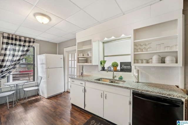 kitchen featuring white refrigerator, sink, light stone countertops, black dishwasher, and white cabinetry