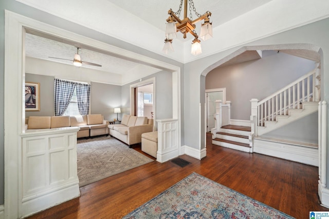 living room with a textured ceiling, ceiling fan, and dark wood-type flooring