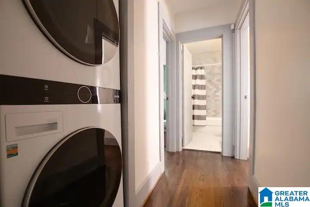 clothes washing area featuring stacked washer / dryer and dark wood-type flooring