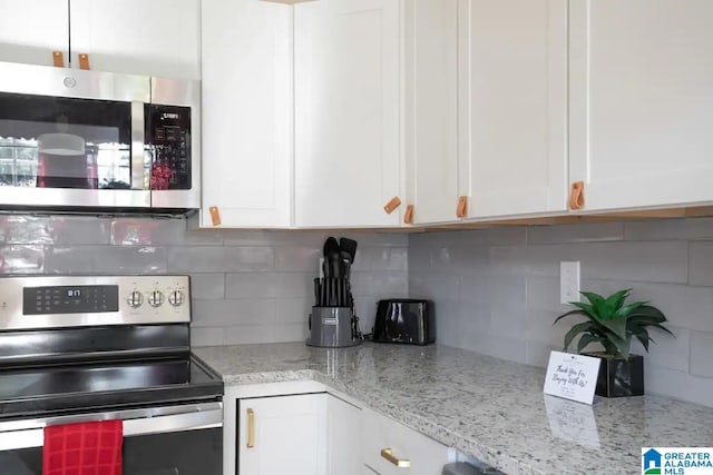 kitchen with tasteful backsplash, white cabinetry, light stone countertops, and stainless steel appliances