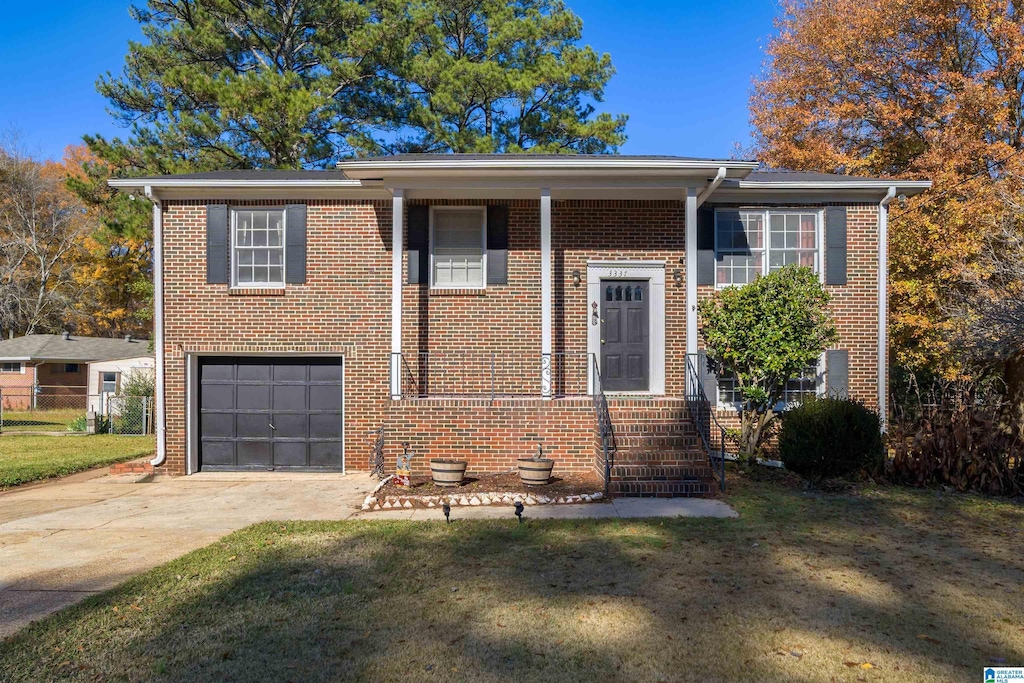 raised ranch featuring a front lawn and a garage