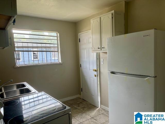 kitchen with range, white fridge, white cabinetry, and sink