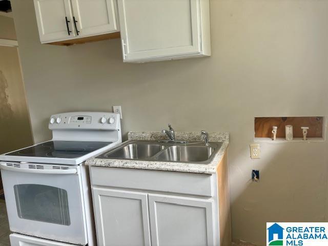 kitchen with white cabinetry, sink, and white electric range