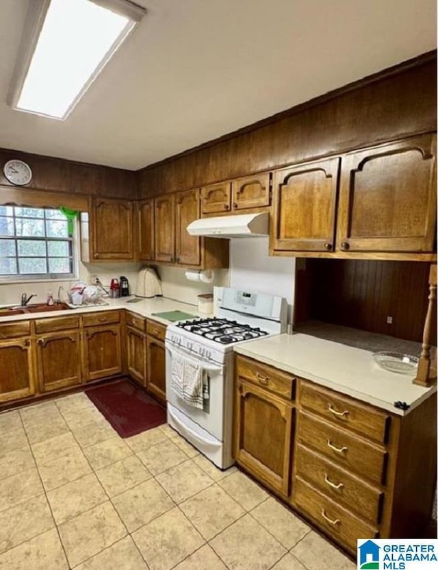 kitchen featuring light tile patterned floors, white gas range oven, and sink