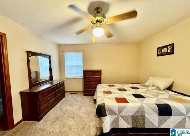 bedroom featuring ceiling fan, light colored carpet, and a textured ceiling