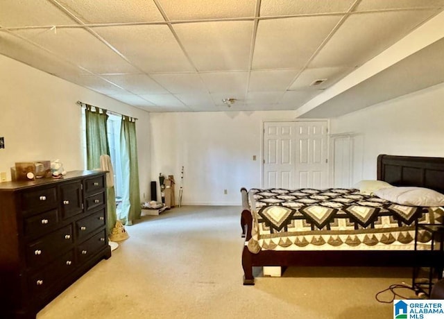 carpeted bedroom featuring a paneled ceiling and a closet