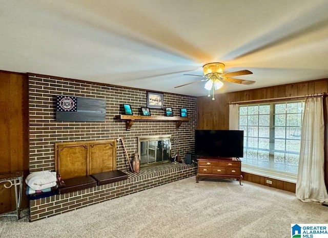 sitting room with carpet flooring, wooden walls, a fireplace, and ceiling fan