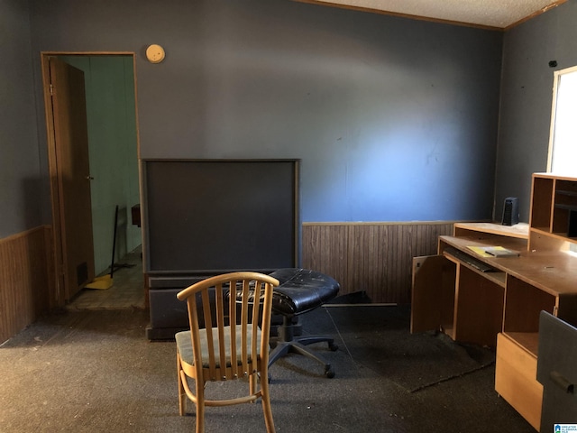 carpeted office space featuring a textured ceiling and wood walls