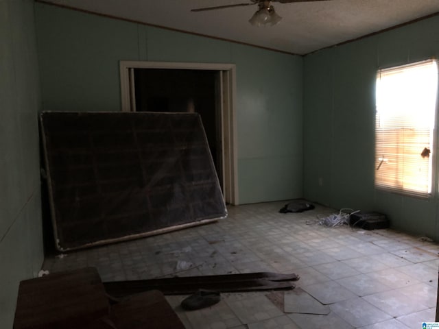 empty room with ceiling fan, a healthy amount of sunlight, lofted ceiling, and a textured ceiling