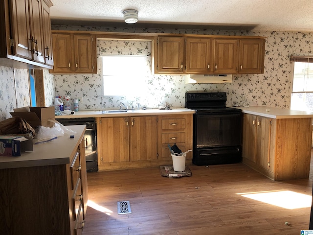 kitchen featuring light hardwood / wood-style flooring, black appliances, and a textured ceiling