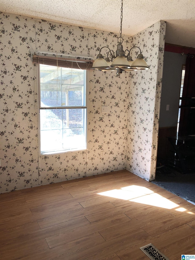 spare room featuring hardwood / wood-style flooring, a textured ceiling, and a chandelier